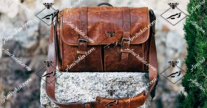 کیف چرم قهوه ای روشن روی یک تکه سنگ