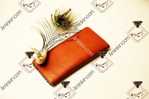 کیف پول چرم در کنار پر طاووس 